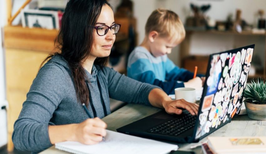 A woman working on a laptop with a child in front of her.