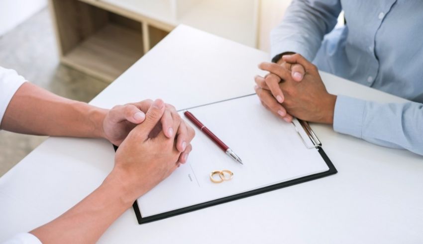 Two people sitting at a table and holding wedding rings.
