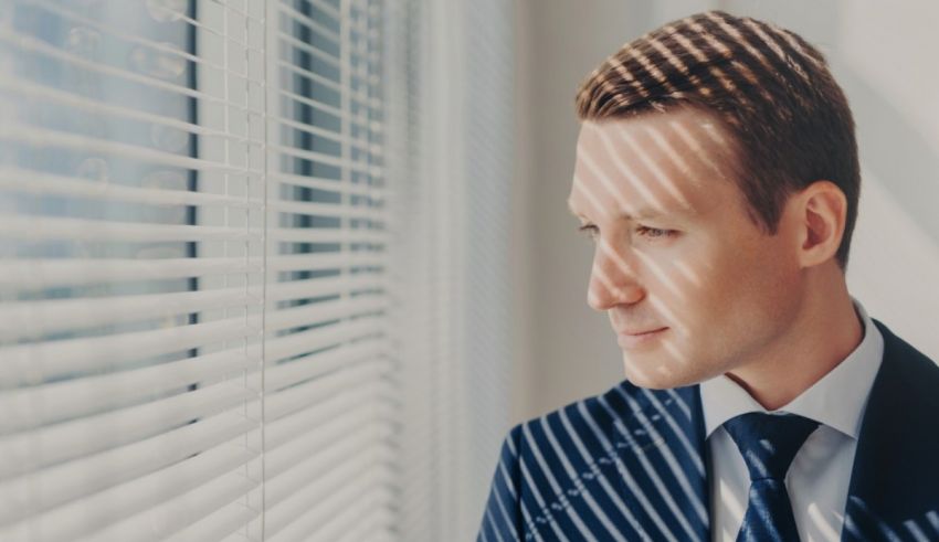 A man in a suit looking out a window.