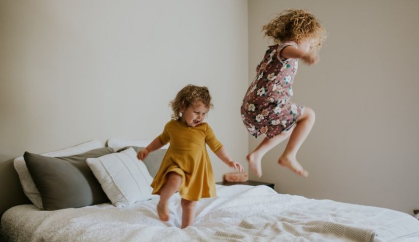 Two little girls jumping on a bed.