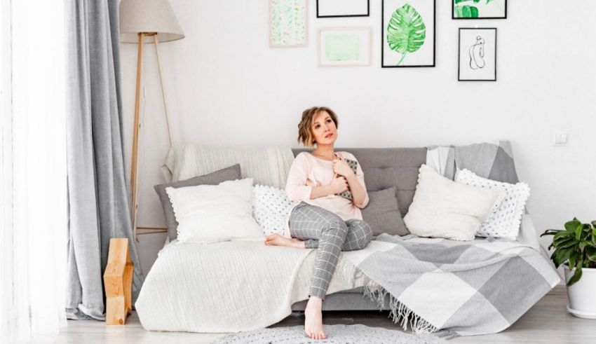 A young woman sitting on a couch in her home.