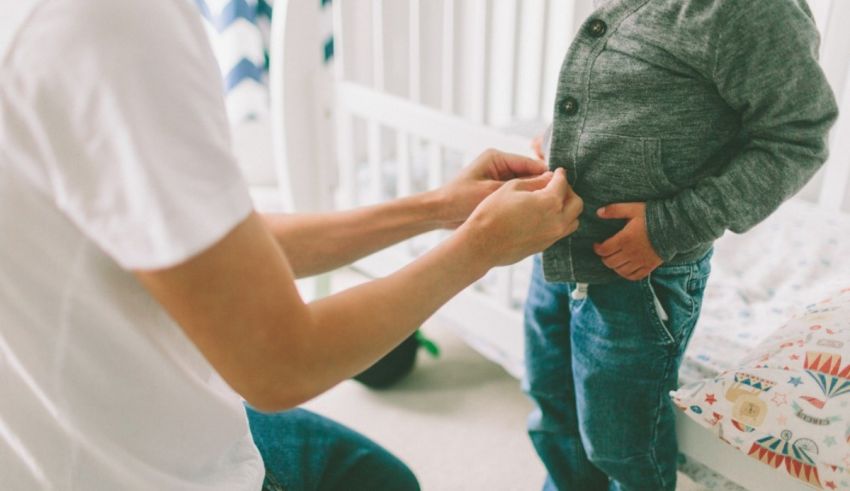 A man is putting on a child's jacket.