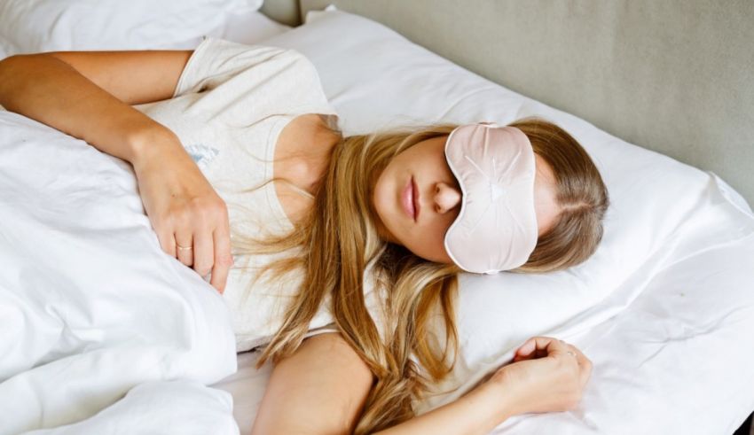 A young woman sleeping in bed with a pink eye mask.