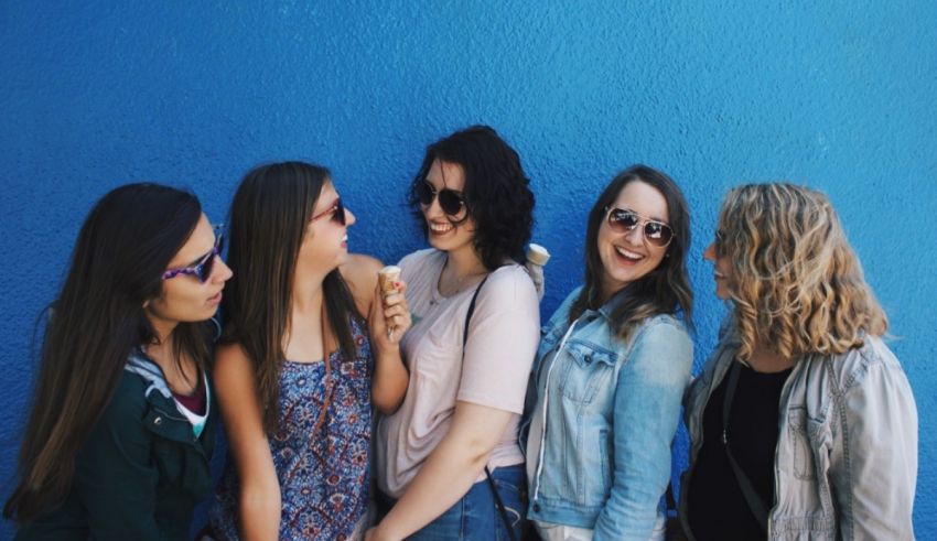 A group of friends laughing in front of a blue wall.