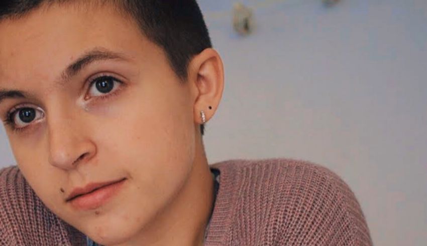 A young girl with a shaved head and pierced ears.