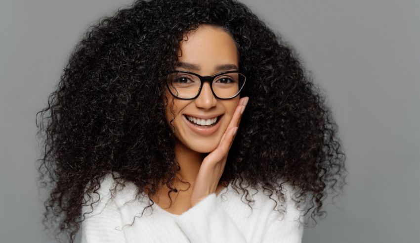 A black woman with curly hair wearing glasses and smiling.