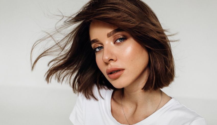 A woman in a white t - shirt with brown hair.