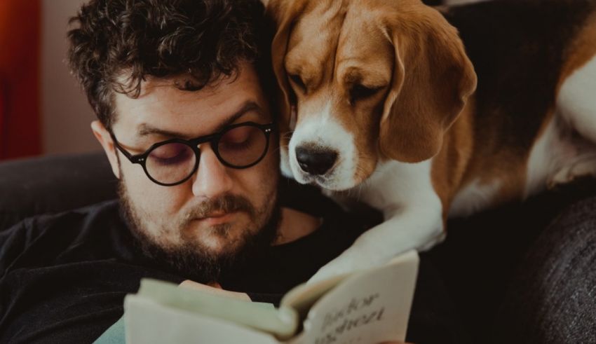 A man reading a book to his dog.