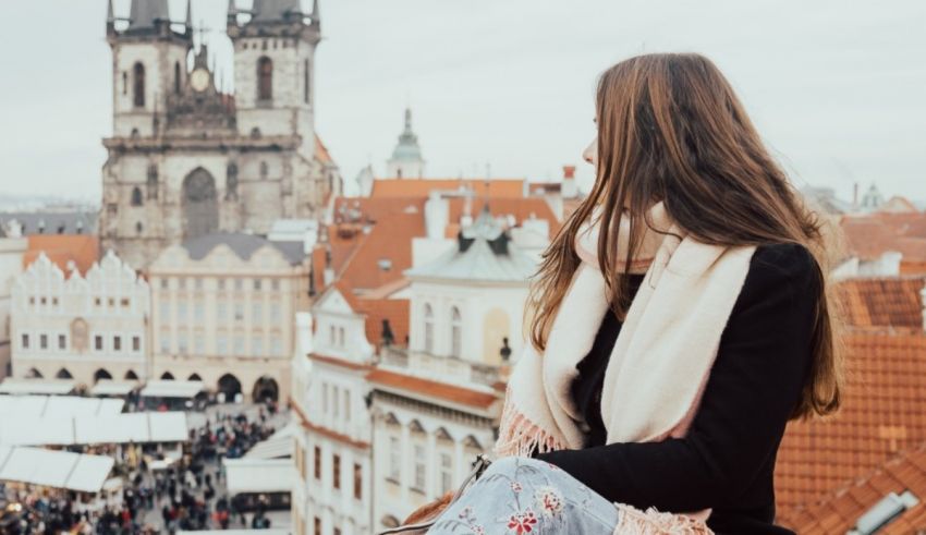 A woman is sitting on a ledge overlooking the city of prague.