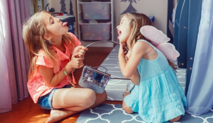 Two little girls sitting on the floor in a room.