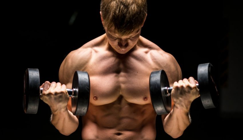 A man lifting dumbbells on a dark background.