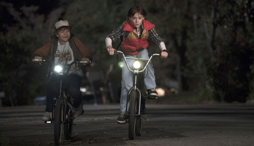 Two people riding bicycles at night in a dark street.