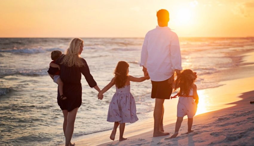 A family is walking on the beach at sunset.