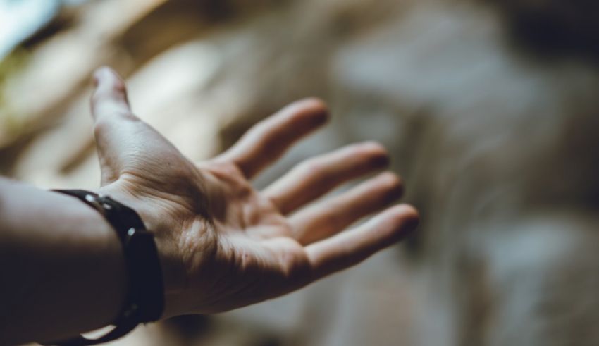 A person's hand reaching out to a rock.