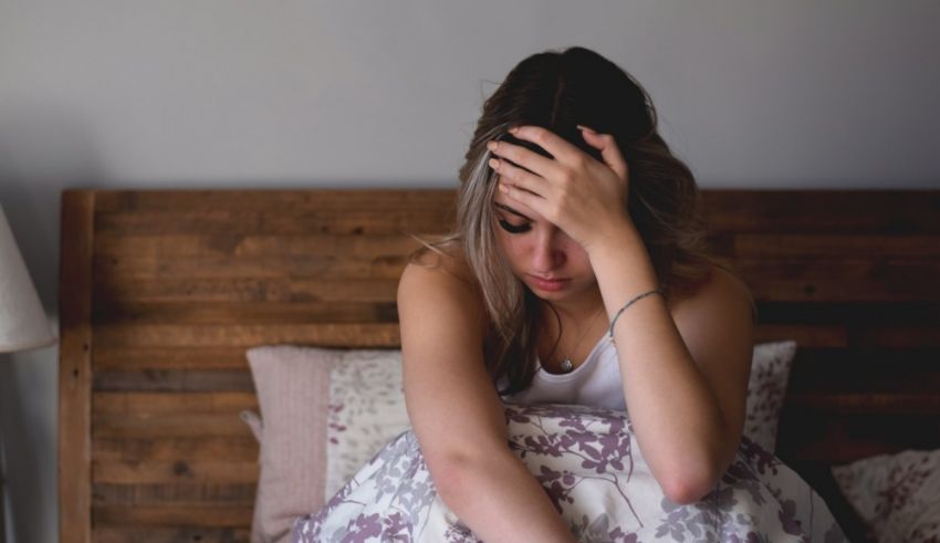 A woman is sitting on a bed with her head on her head.