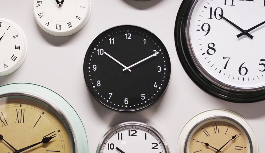 A group of clocks on a white wall.