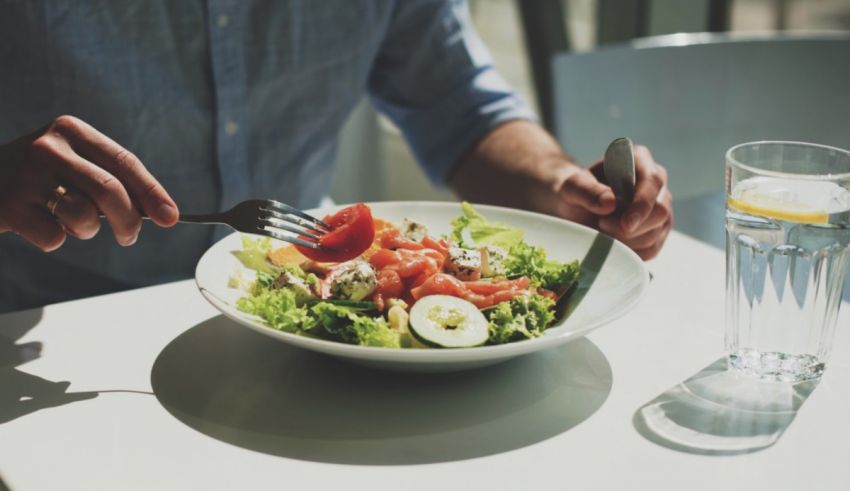 A man is eating a salad with a fork.