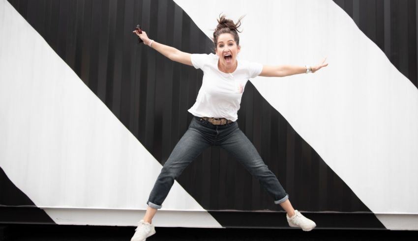 A woman jumping in front of a black and white striped wall.