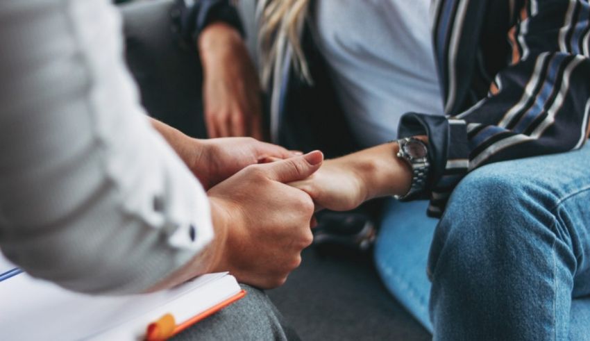 A woman is holding a man's hand while sitting on a couch.