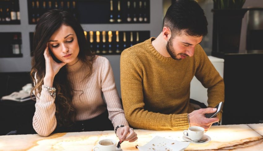 A man and woman sitting at a table looking at their phones.