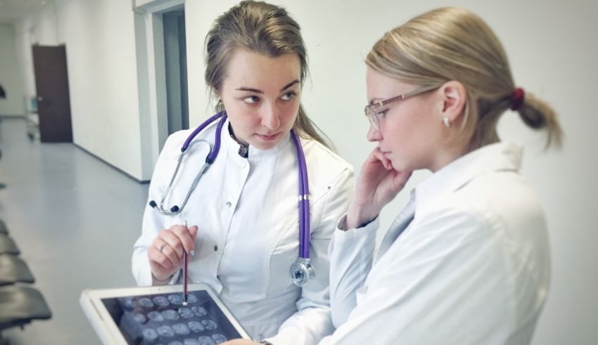 Two doctors looking at an x - ray on a tablet.