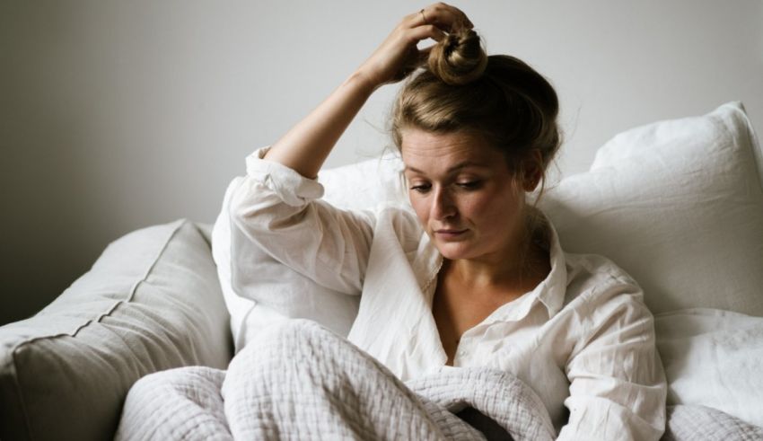 A woman is sitting on a couch with her head in her hands.