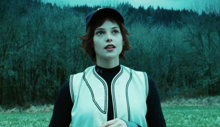 A woman in a baseball uniform standing in a field.