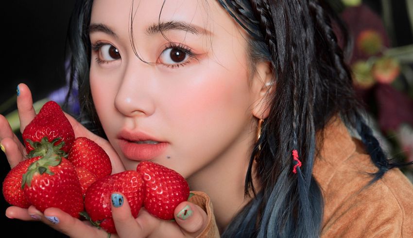 A girl holding a bunch of strawberries in her hand.