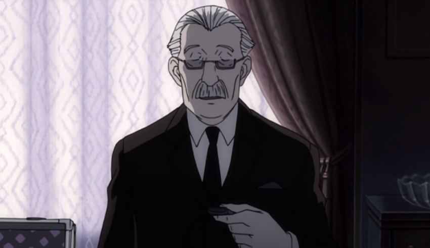A man in a suit and tie is standing in front of a window.