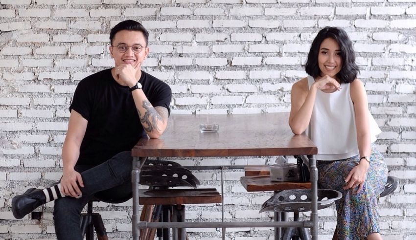 Two people sitting at a table in front of a brick wall.
