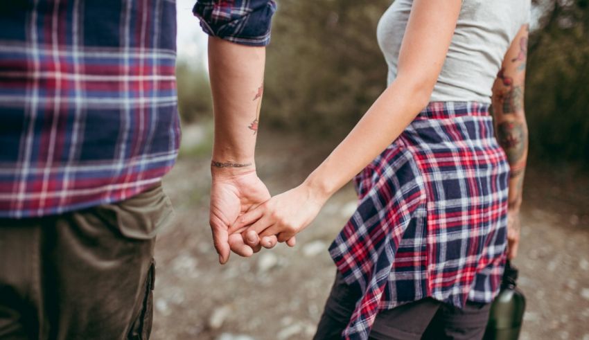 A man and woman holding hands in the woods.