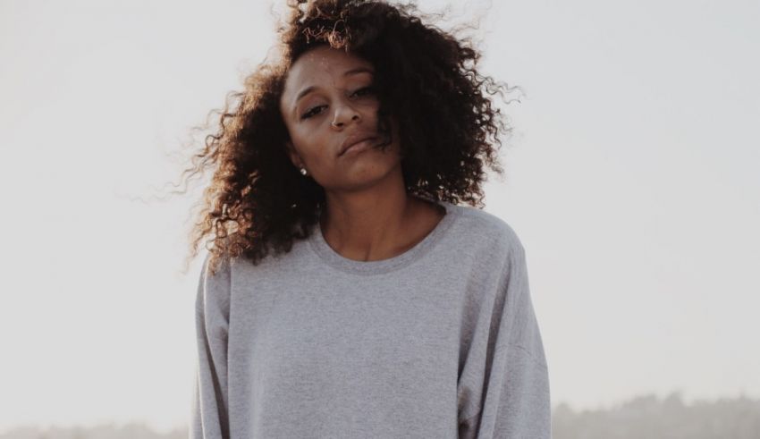 A woman with curly hair standing in a field.