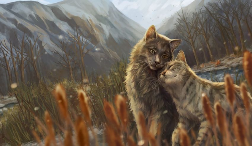 Two cats standing in the grass near a mountain.
