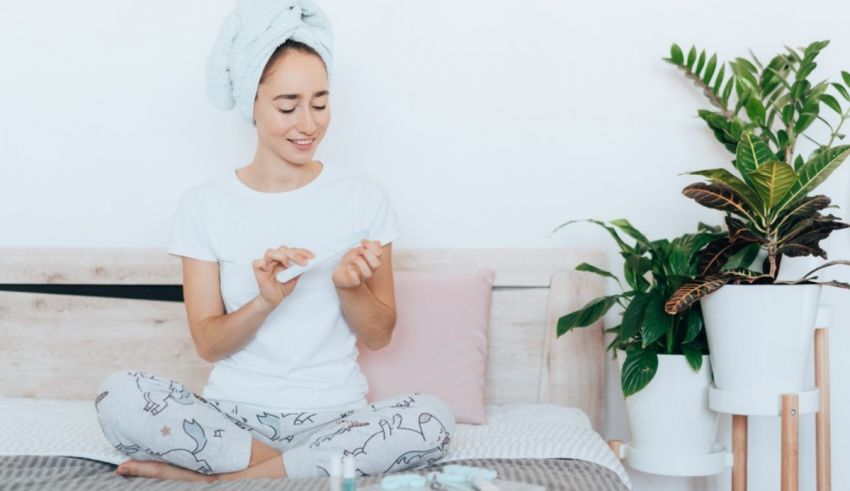 A woman is sitting on a bed with a towel on her head.