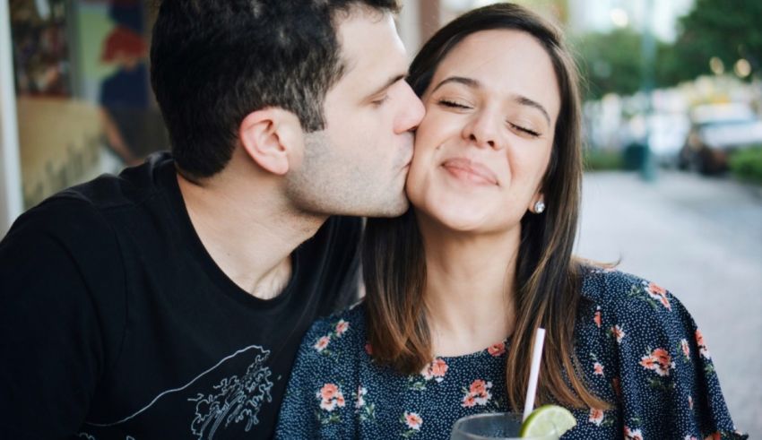A man and woman kissing in front of a bar.