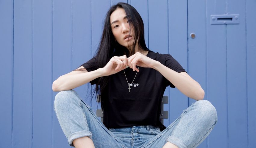 A woman sitting on a bench wearing a black t - shirt and jeans.