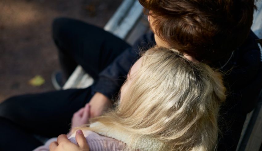 A man and a woman hugging on a bench.