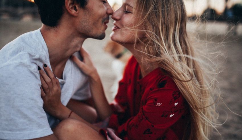 A man and woman kissing on the beach.
