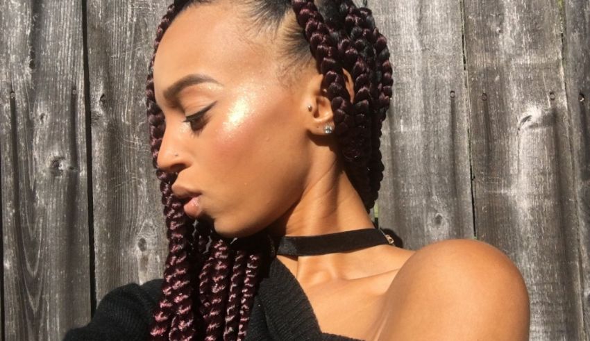 A woman wearing a black top and purple braids.