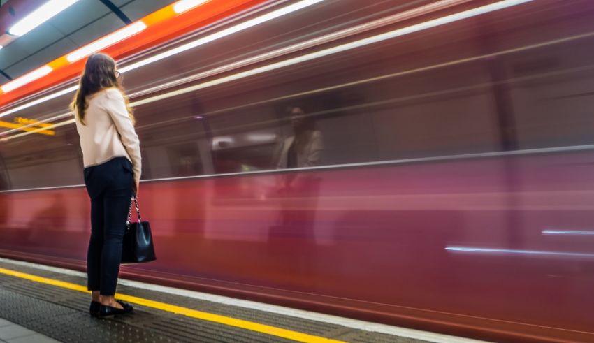 A woman standing on a platform waiting for a train.