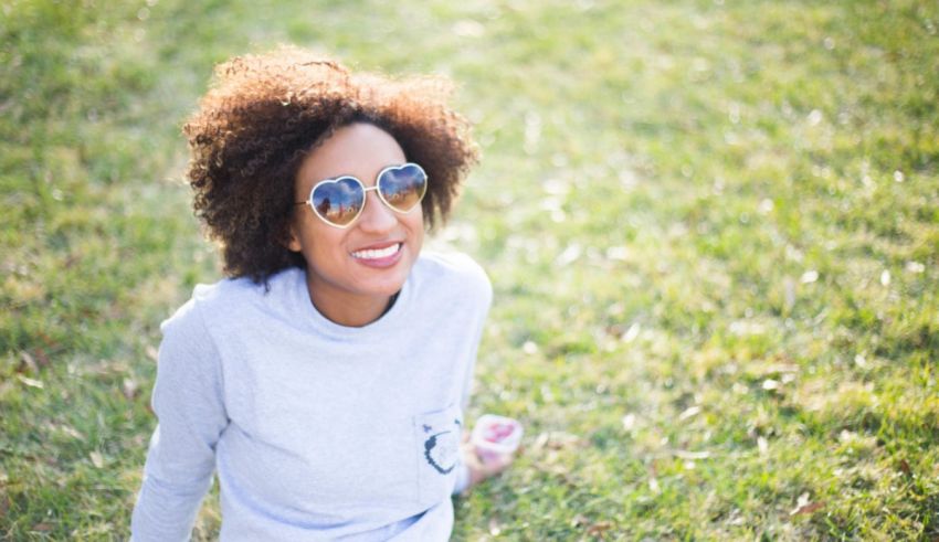 A woman wearing sunglasses laying on the grass.