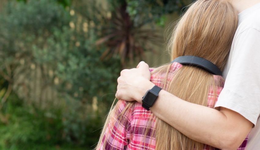 A man and woman hugging each other in a park.