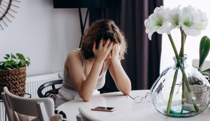 A woman is sitting at a table with her hands on her face.