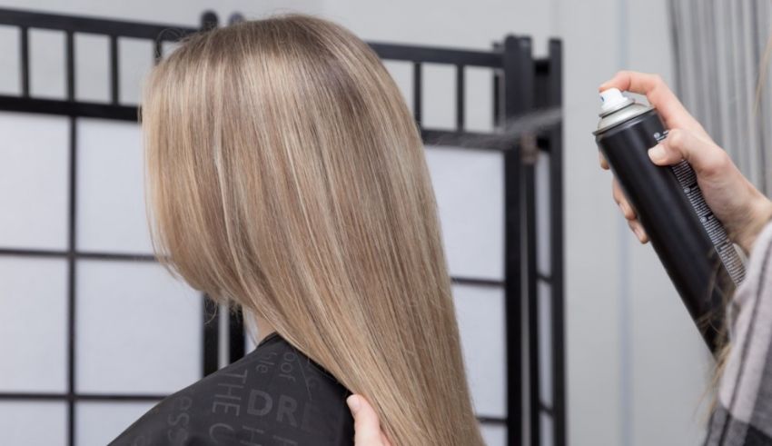 A woman is getting her hair sprayed in a salon.