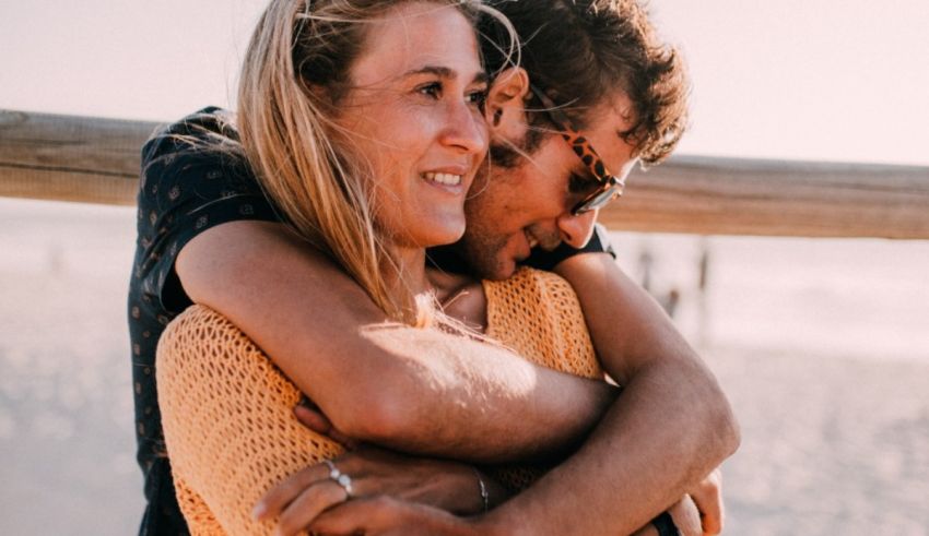 A man and woman hugging on the beach.