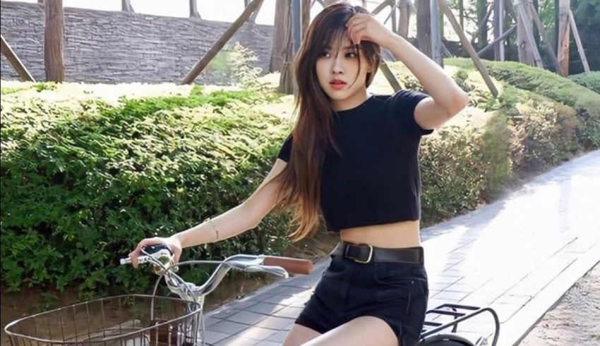 A girl sitting on a bicycle with a black top and black shorts.