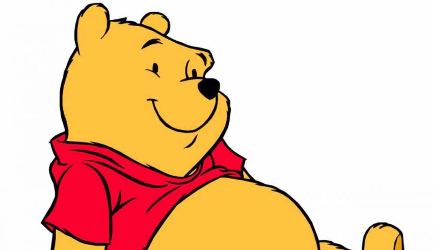 Winnie the pooh sitting down in a red shirt.
