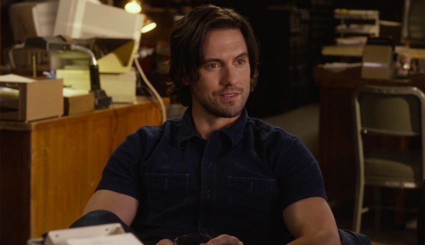 A man in a blue shirt sitting at a desk.