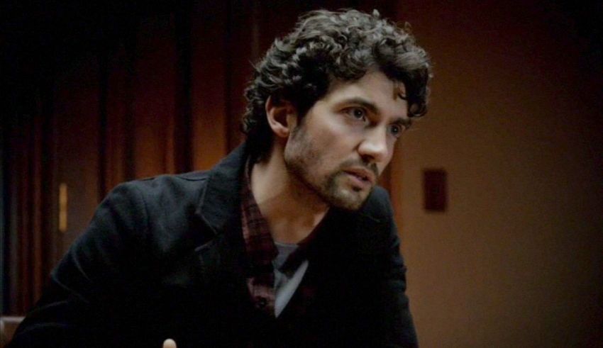 A man with curly hair sitting at a table.