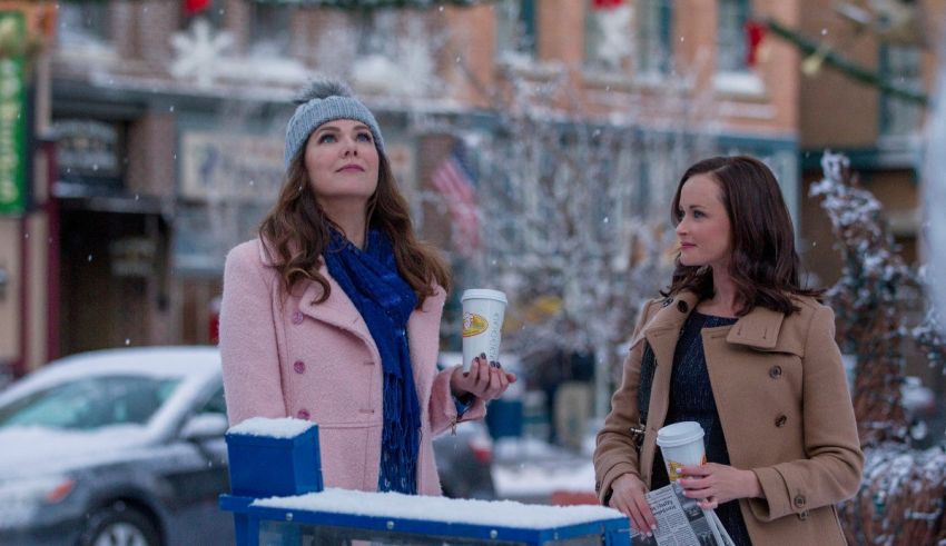 Two women standing in a snowy street with coffee cups.